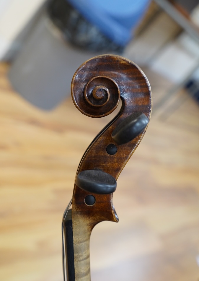 An early 20th century German violin, with a label reading ‘Copy of Joseph Guarnerius, Made in Germany’, body length 35.5cm, cased with a bow by Tourte. Condition - good.